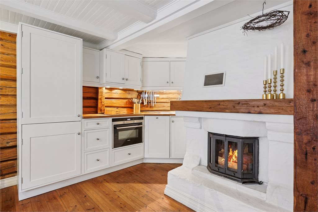 Kjøkkenet har en tidløs og delikat innredning med hvite fronter og integrerte hvitevarer. 