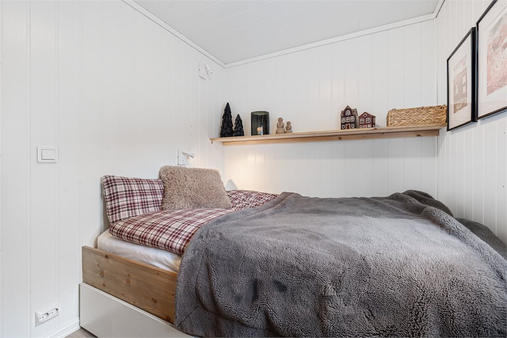Lyst og hyggelig soverom med plassbygget seng og praktiske oppbevaringsmuligheter.