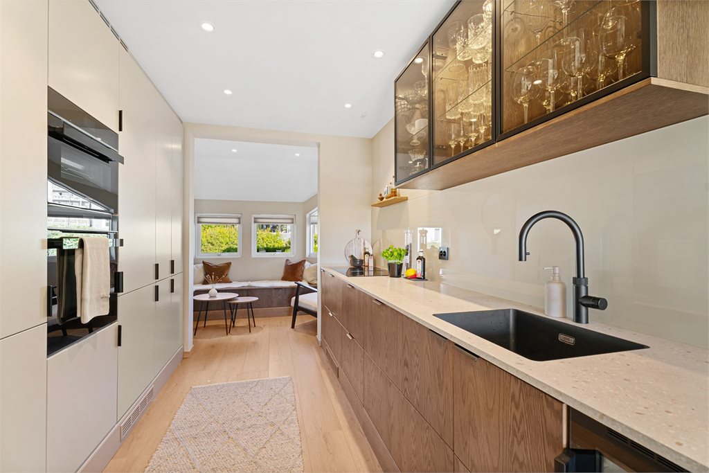 Kjøkkenet ble pusset opp i 2024 og holder en god standard. Her er det en blanding av tre, slette beige fronter og mindre overskap som skaper en luftig følelse